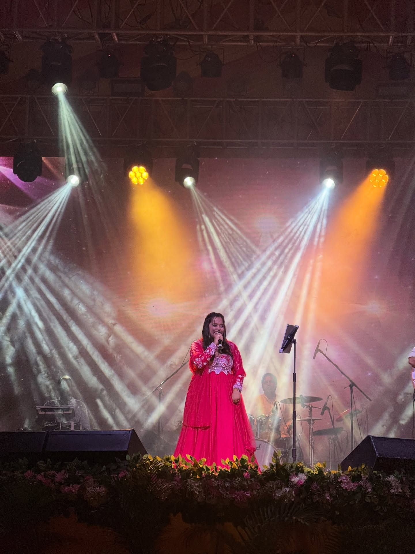 Singer performing with band under amber and white stage beams