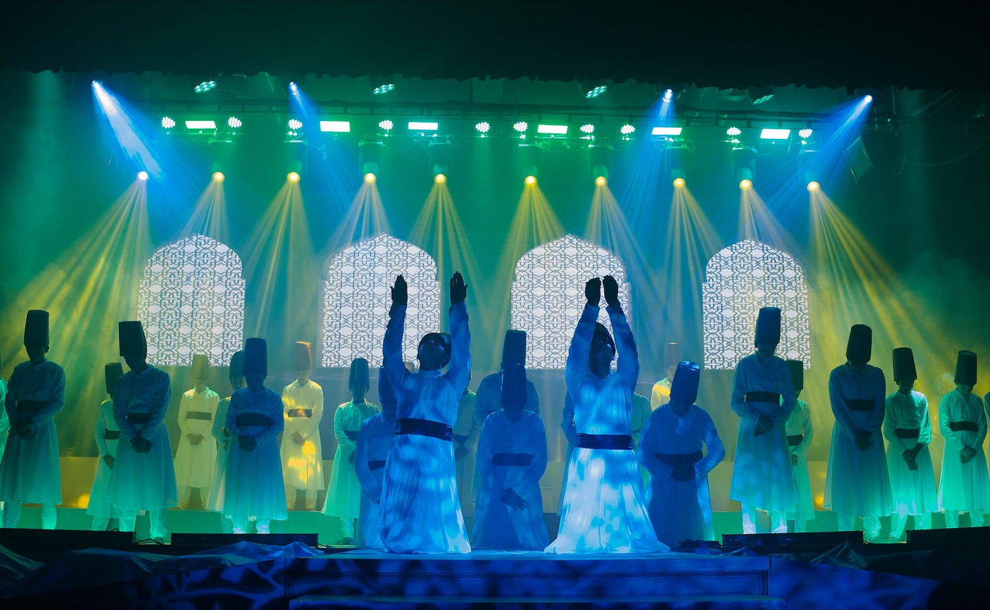 Theatrical stage performance under green, blue and yellow beam lighting